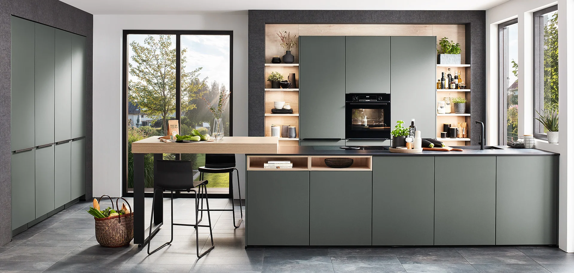Moderne Kücheninnenräume mit eleganten grünen Schränken, integrierten Geräten und einem Induktionskochfeld auf einer dunklen Arbeitsplatte, die zeitgenössischen Stil und Funktionalität ausstrahlen.