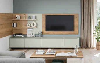 Wohnzimmer mit Lowboard SENSO 494 in Jade und Antifingerprint-Fronten, TV-Wand in Holzoptik und offenen Regalen
