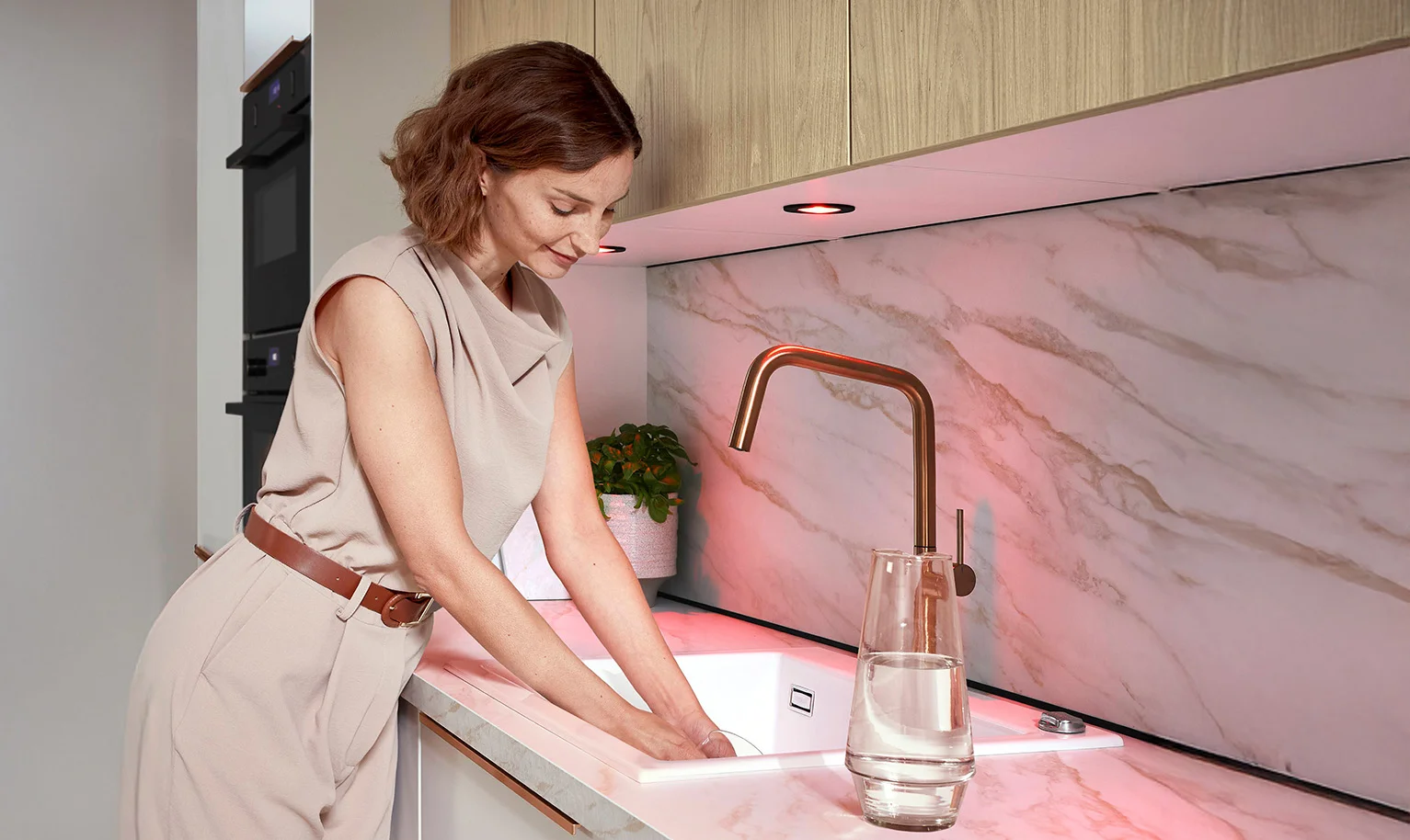 Ergonomischer Spülboden in der Küche – Frau am Spülbecken mit leicht über der Arbeitsplatte positionierten Ellenbogen.