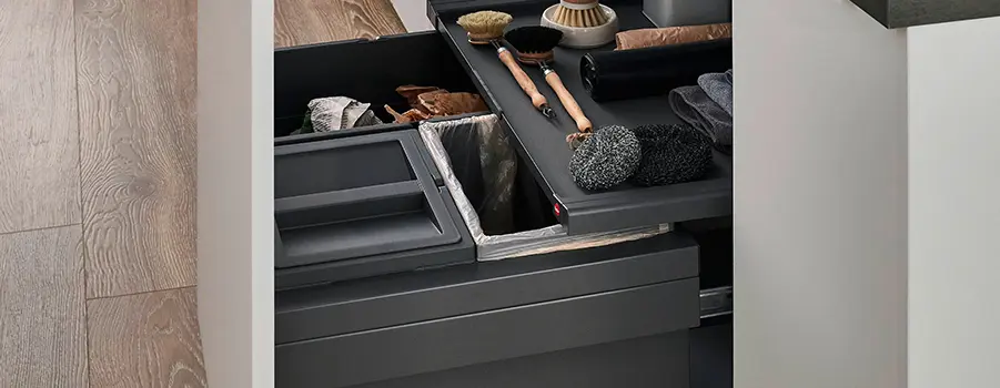 Graue Stauraum-Schublade mit Küchenutensilien und Reinigungssachen sorgfältig organisiert. Küchenfront Senso in Alpinweiß und Antifingerprint-Oberfläche. 