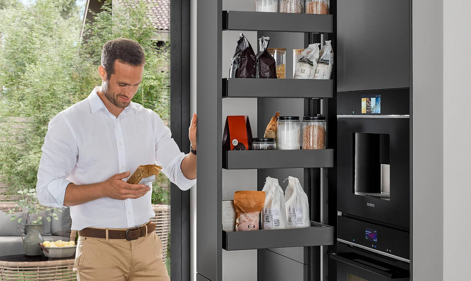 Moderne ergonomische Küche mit Apothekerschrank – Mann nutzt beidseitig zugänglichen Stauraum für schnellen und komfortablen Zugriff.