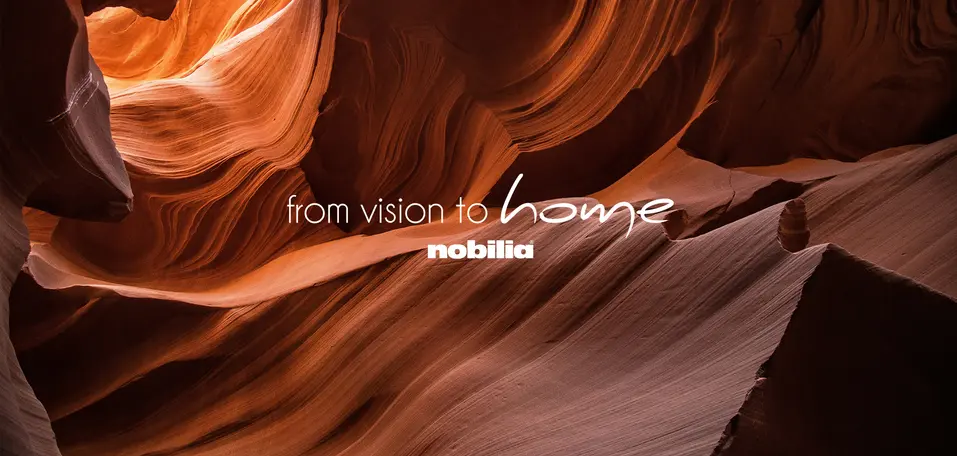 Motiv der nobilia Hausmesse mit dem Motto „from vision to home“ vor geschwungenen, orangefarbenen Felsformationen