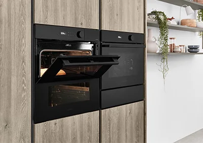 nobilia Kompaktgeräte in schwarzem Design – moderne Einbaubacköfen in ergonomischer Höhe, platzsparend integriert in Holzoptik-Küchenfronten für stilvolle und funktionale Küchenlösungen.
