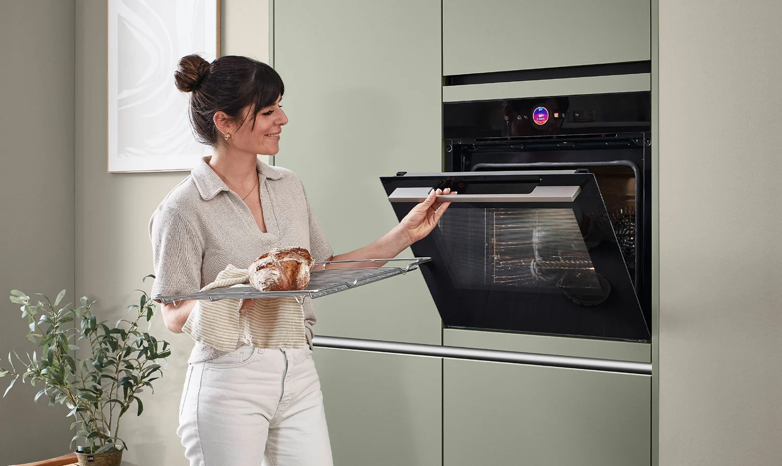 Frau vor Backofen auf Zugriffshöhe in ergonomischer Küche – komfortable und rückenschonende Bedienung