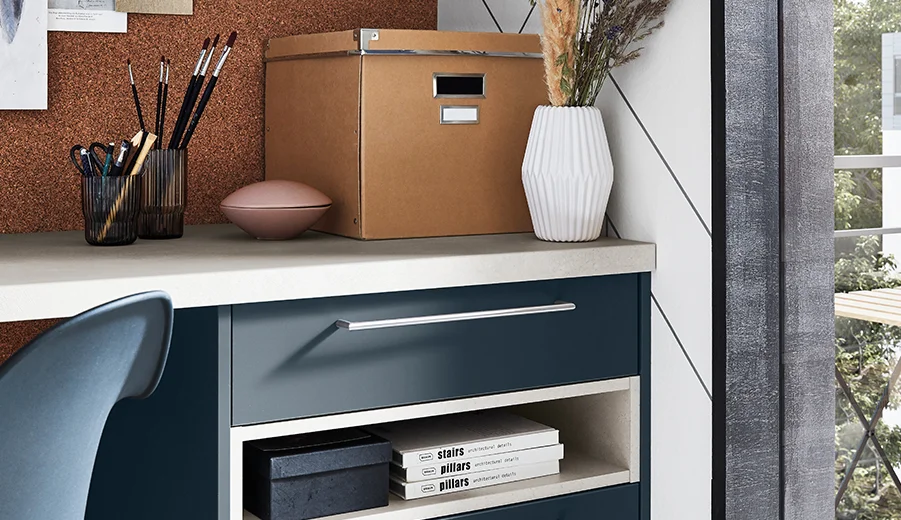 Zeitgemäßes Homeoffice mit einem eleganten blauen Schreibtisch mit organisierten Regalen, stilvollen Aufbewahrungsboxen und dekorativen Gegenständen, die Funktionalität mit moderner Ästhetik verbinden.